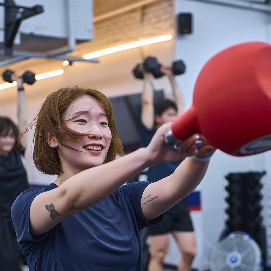 케틀벨을 들어 올리며 웃는 회원